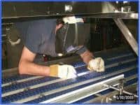 Technician working on bakery conveyor equipment during a service visit